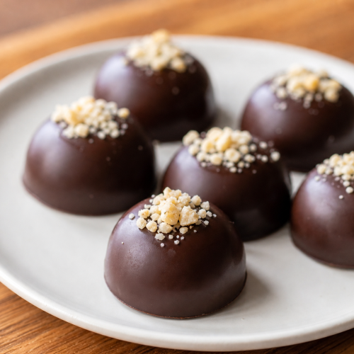 Fat bombs au chocolat sur une assiette blanche, garnies de noix de macadamia, éclairage naturel doux