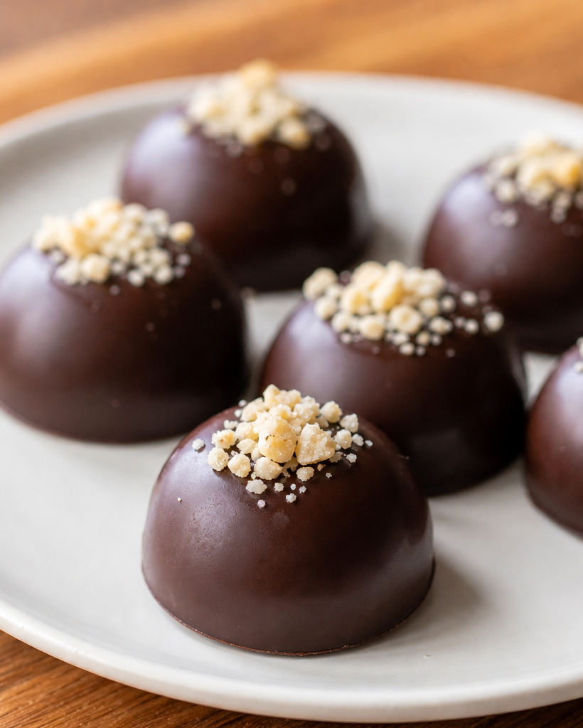 Fat bombs au chocolat sur une assiette blanche, garnies de noix de macadamia, éclairage naturel doux