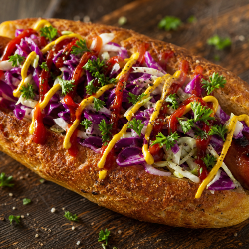 Hot dog cétogène sur planche en bois, pain doré, saucisse, coleslaw au chou rouge et blanc, ketchup et moutarde
