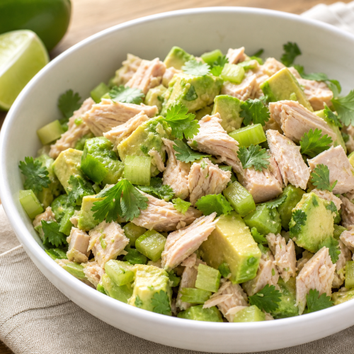 Bol de salade thon avocat keto avec coriandre et céleri, présenté sur une table en bois, éclairage naturel