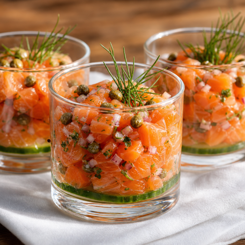 Trois verrines de tartare de saumon avec aneth et concombre sur fond bois
