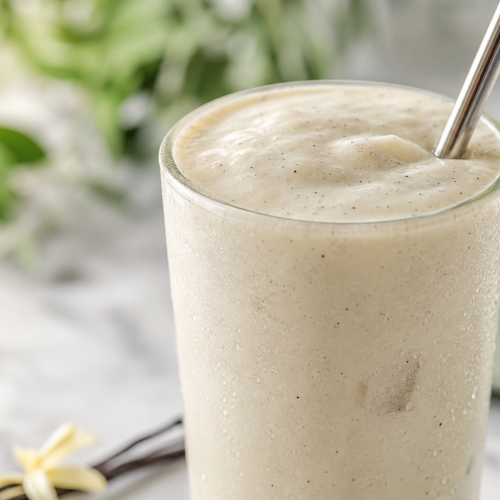 Grand verre de milk shake kéto à la vanille, crémeux et sans sucre, avec une paille métallique